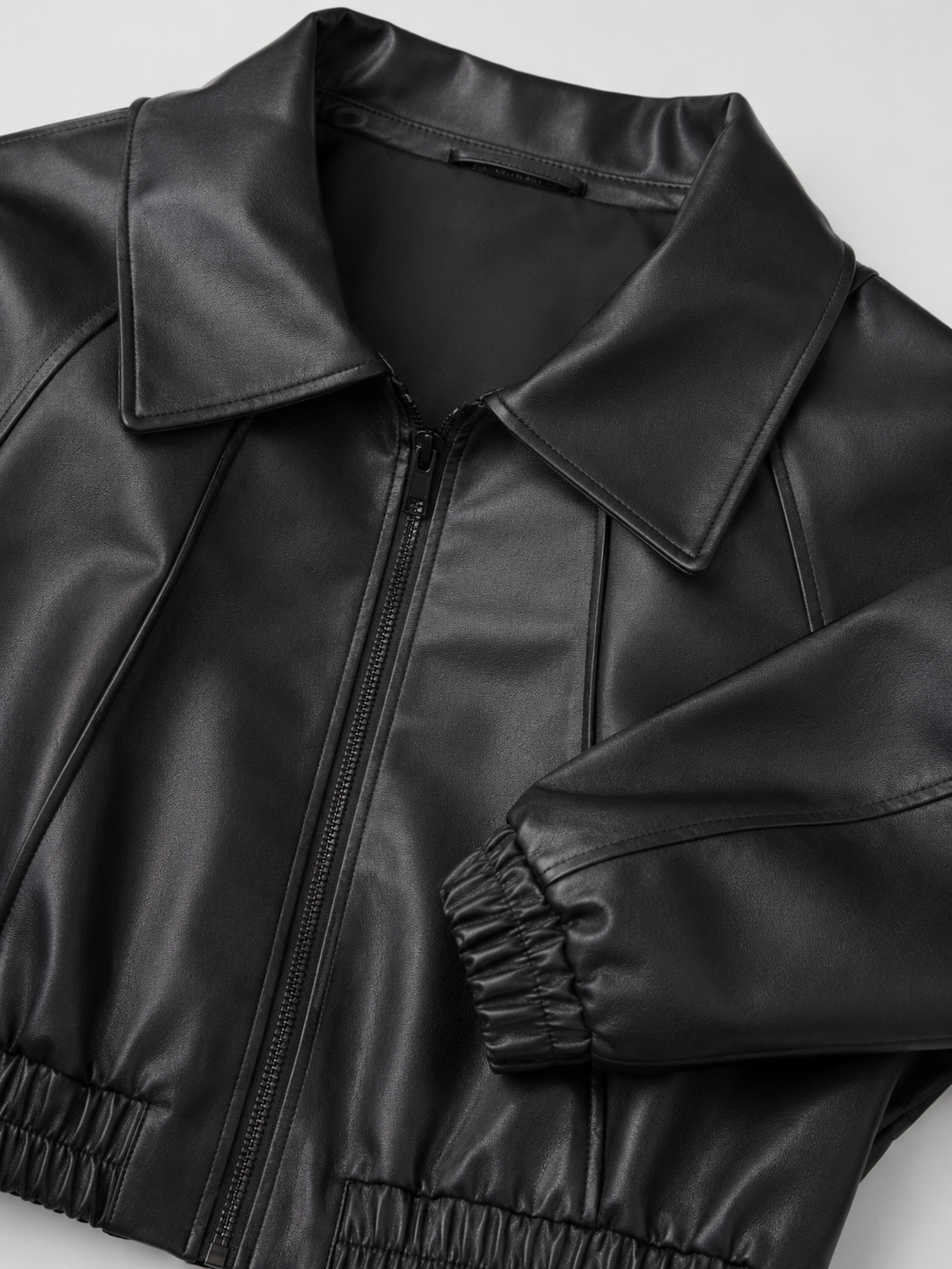 Woman wearing a cropped faux leather biker jacket with notch lapels