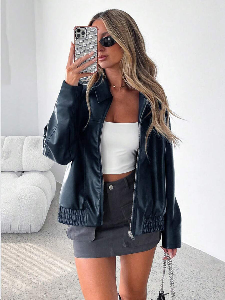 Woman wearing an oversized faux leather jacket with a wide collar and gathered hem