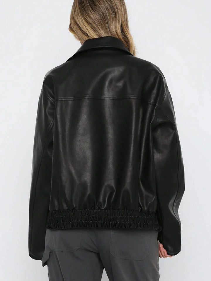 Woman wearing an oversized faux leather jacket with a wide collar and gathered hem