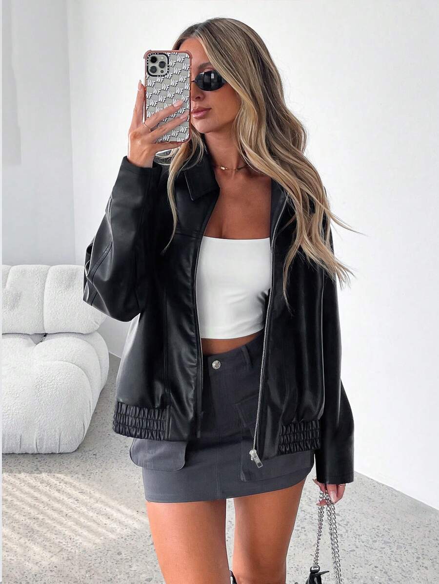 Woman wearing an oversized faux leather jacket with a wide collar and gathered hem