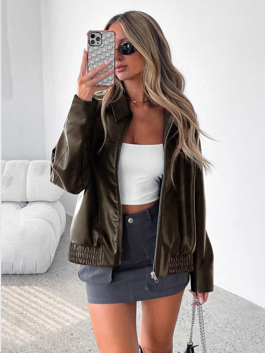 Woman wearing an oversized faux leather jacket with a wide collar and gathered hem