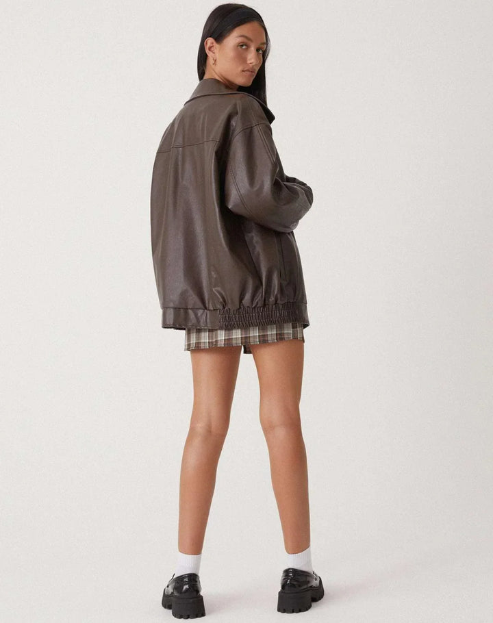 Woman wearing a boxy oversized faux leather jacket with a point collar