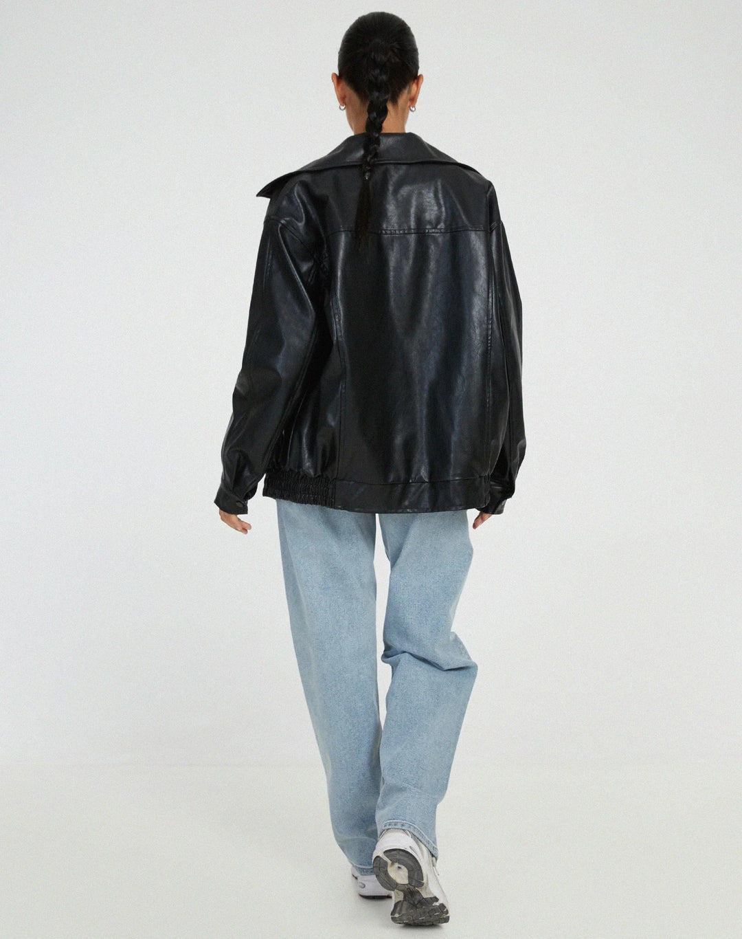 Woman wearing a boxy oversized faux leather jacket with a point collar