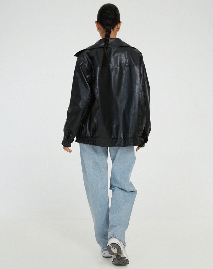 Woman wearing a boxy oversized faux leather jacket with a point collar