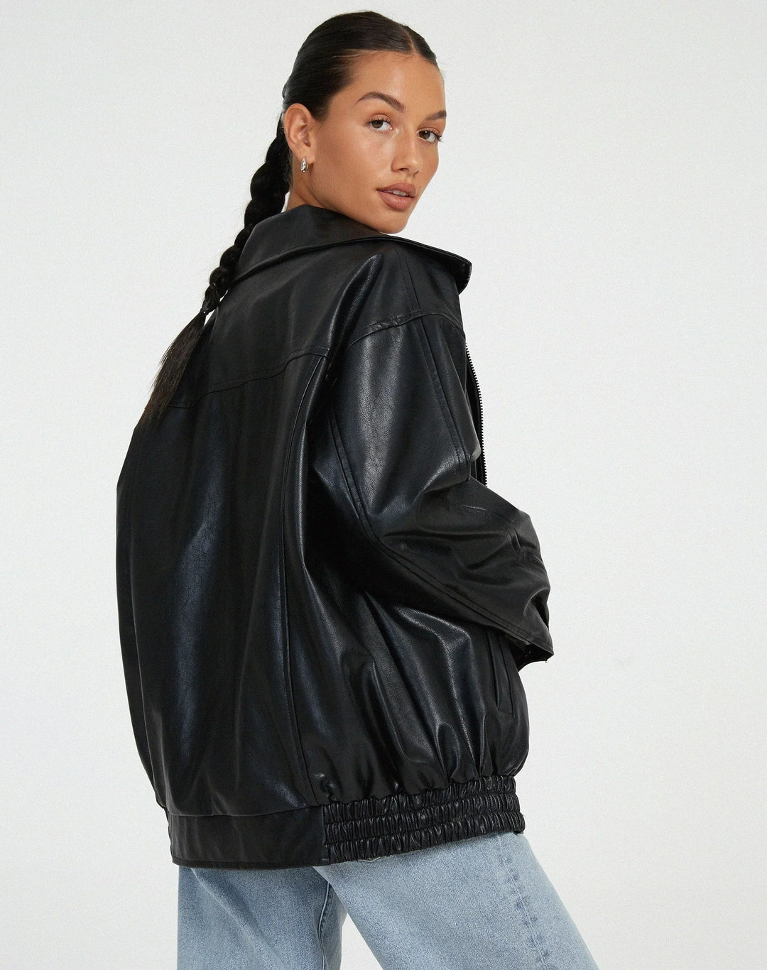 Woman wearing a boxy oversized faux leather jacket with a point collar