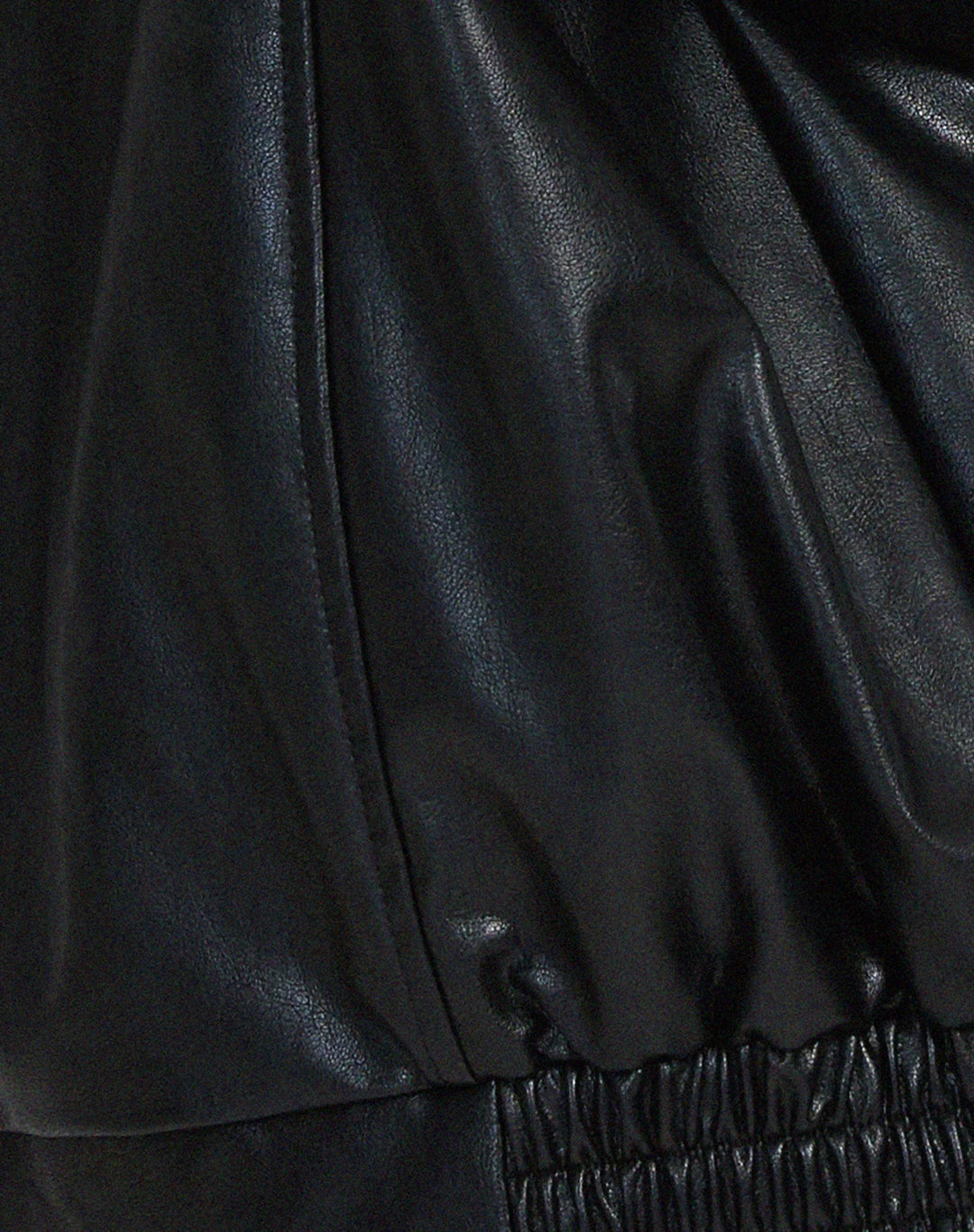 Woman wearing a boxy oversized faux leather jacket with a point collar