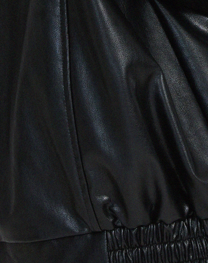 Woman wearing a boxy oversized faux leather jacket with a point collar